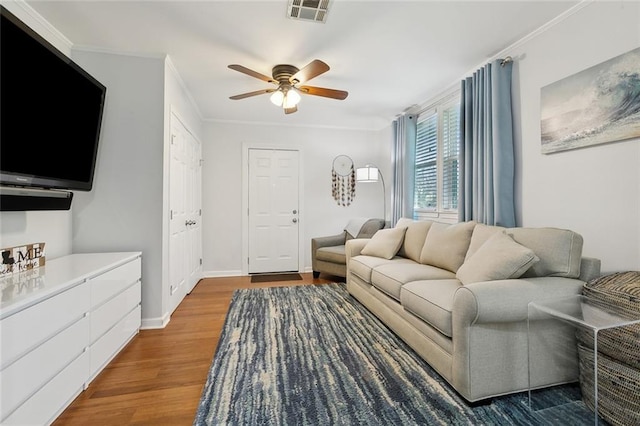 living area with baseboards, visible vents, ceiling fan, wood finished floors, and crown molding