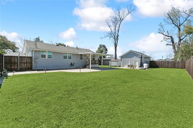 back of house with a yard, an outbuilding, a fenced backyard, and a patio