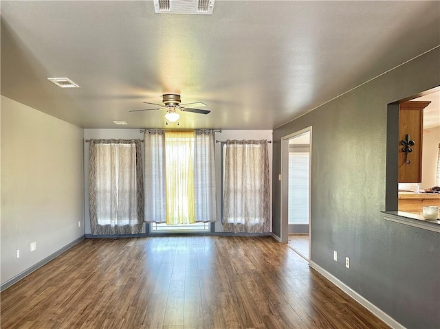 spare room featuring a ceiling fan, baseboards, visible vents, and wood finished floors