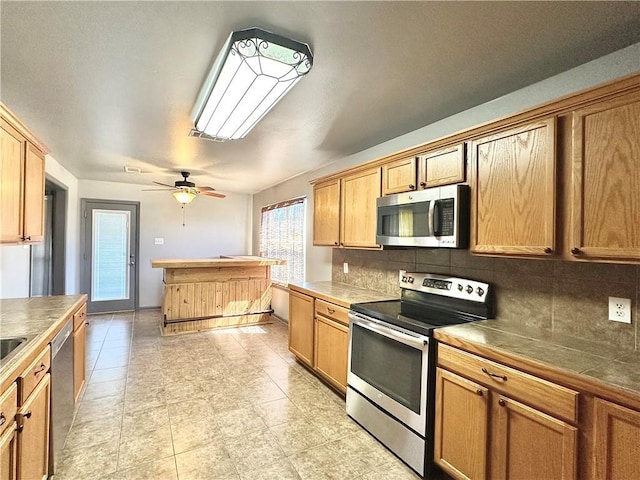 kitchen with appliances with stainless steel finishes, backsplash, and a ceiling fan