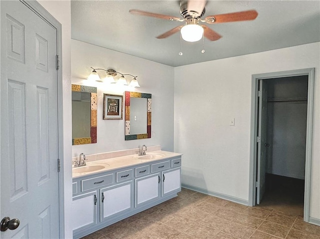full bath with double vanity, ceiling fan, baseboards, and a sink