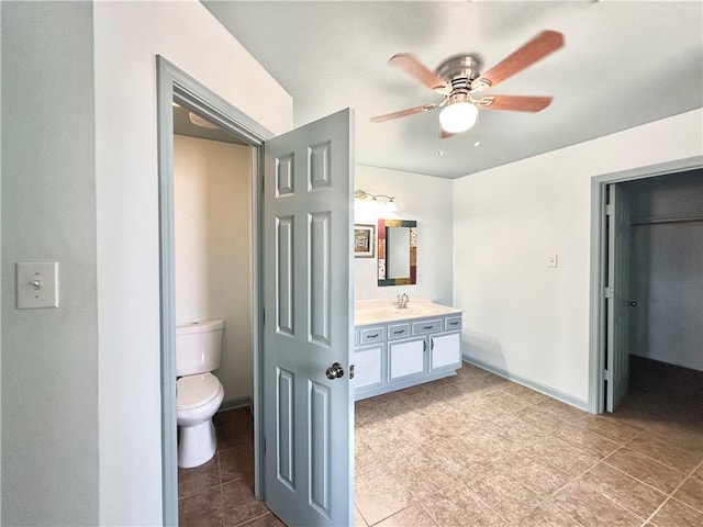bathroom featuring toilet, baseboards, a ceiling fan, and vanity