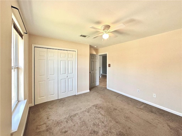 unfurnished bedroom with baseboards, visible vents, ceiling fan, carpet floors, and a closet