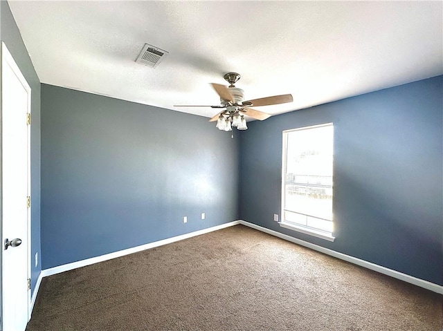 carpeted empty room featuring a ceiling fan, visible vents, a textured ceiling, and baseboards