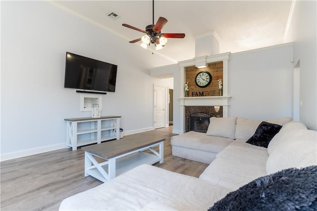 living room with a large fireplace, visible vents, baseboards, and wood finished floors