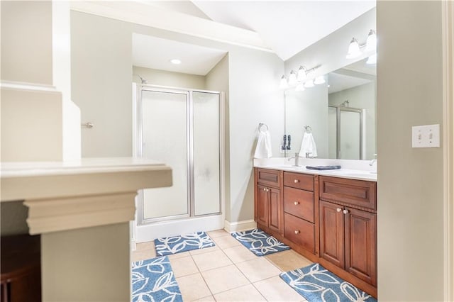 bathroom featuring double vanity, vaulted ceiling, a shower stall, tile patterned flooring, and baseboards