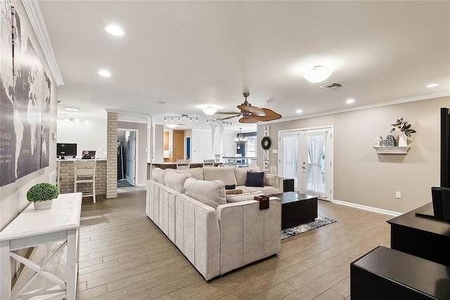 living room featuring visible vents, crown molding, light wood-type flooring, a fireplace, and recessed lighting