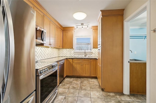 kitchen with light tile patterned floors, tasteful backsplash, dark stone counters, stainless steel appliances, and a sink