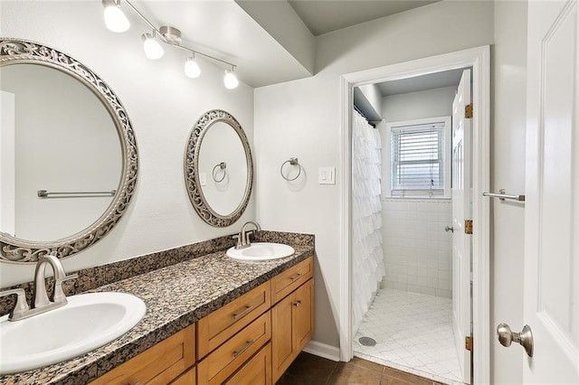 bathroom featuring double vanity, a sink, and tiled shower