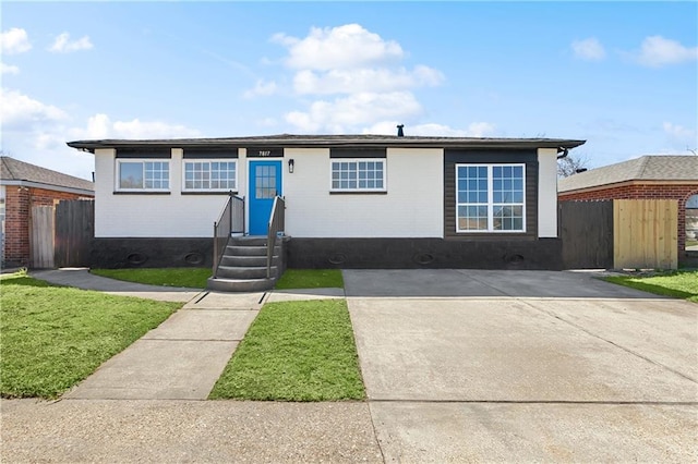 ranch-style home featuring entry steps, fence, and a front lawn