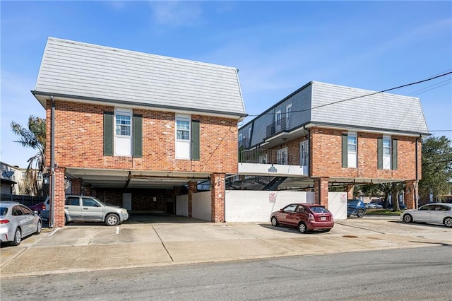 view of front facade with covered and uncovered parking and brick siding