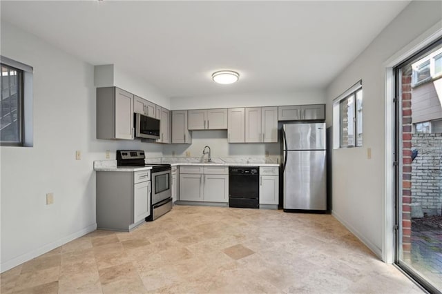 kitchen featuring stainless steel appliances, a sink, light countertops, and gray cabinetry