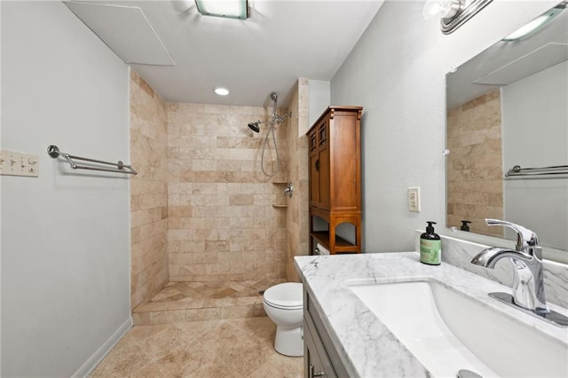 bathroom featuring a tile shower, vanity, and toilet