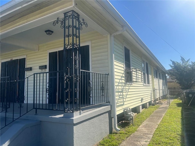 view of home's exterior with a porch and fence