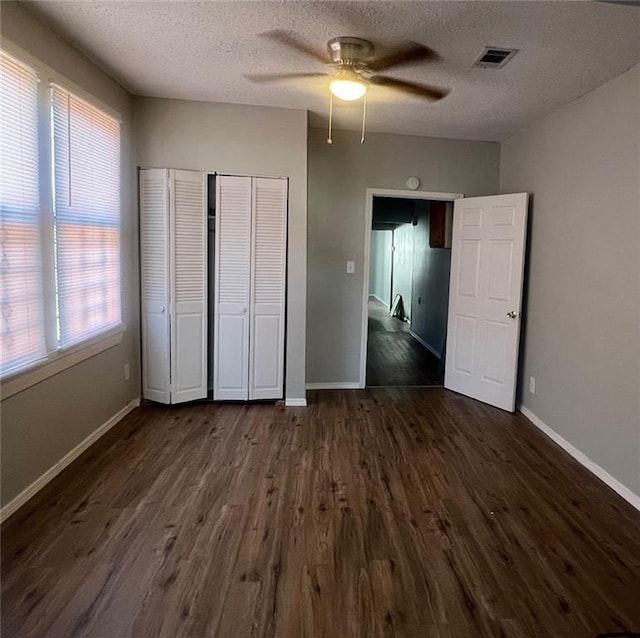 unfurnished bedroom featuring visible vents, baseboards, and dark wood-style floors