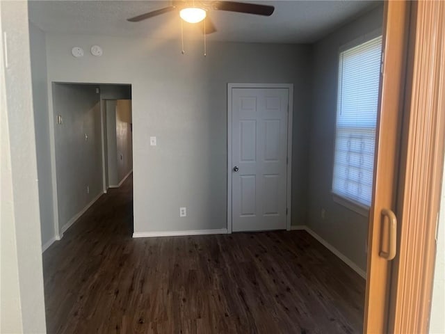 spare room with dark wood-style floors, baseboards, and ceiling fan