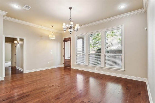 empty room with crown molding, visible vents, an inviting chandelier, wood finished floors, and baseboards