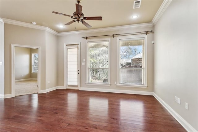 spare room featuring baseboards, wood finished floors, visible vents, and crown molding