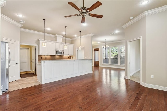 kitchen with ceiling fan with notable chandelier, stainless steel appliances, dark wood-style flooring, and backsplash