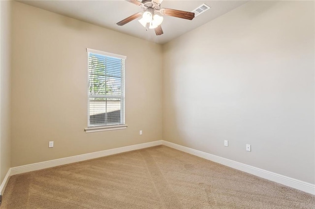 empty room featuring a ceiling fan, light colored carpet, visible vents, and baseboards