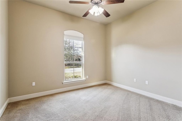 carpeted spare room with a ceiling fan and baseboards