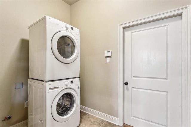 clothes washing area featuring stacked washer and dryer, baseboards, and laundry area