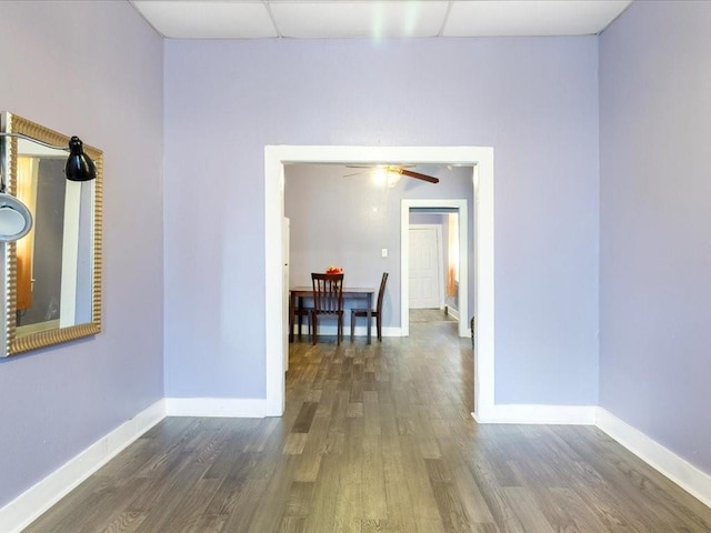 empty room with a drop ceiling, baseboards, and wood finished floors