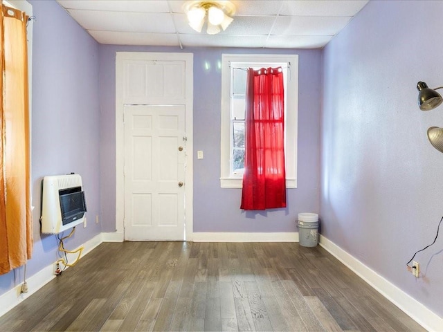 entryway with heating unit, a paneled ceiling, baseboards, and wood finished floors