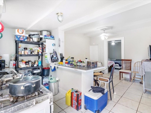 kitchen with a ceiling fan, a breakfast bar, and light tile patterned floors