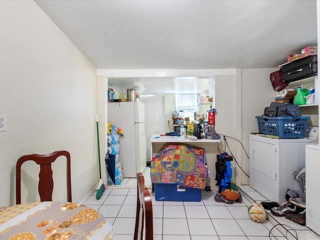 kitchen featuring freestanding refrigerator, light countertops, washer and clothes dryer, and light tile patterned floors
