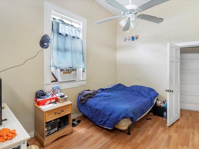 bedroom featuring light wood-style floors, cooling unit, ceiling fan, and baseboards