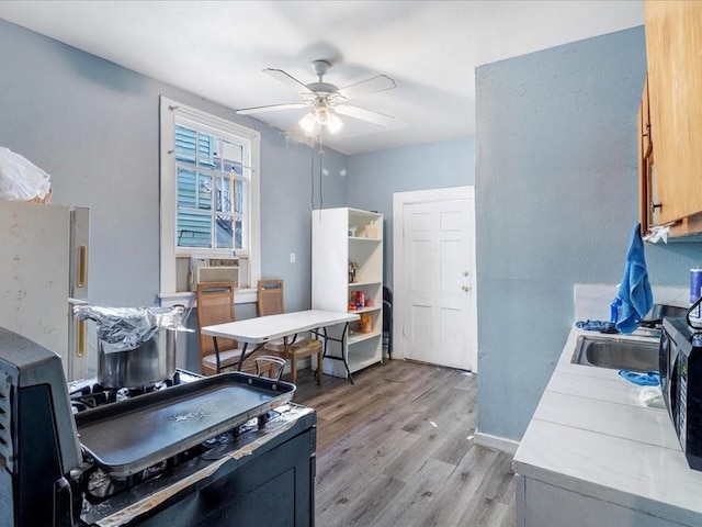 office space featuring baseboards, cooling unit, a ceiling fan, and light wood-style floors