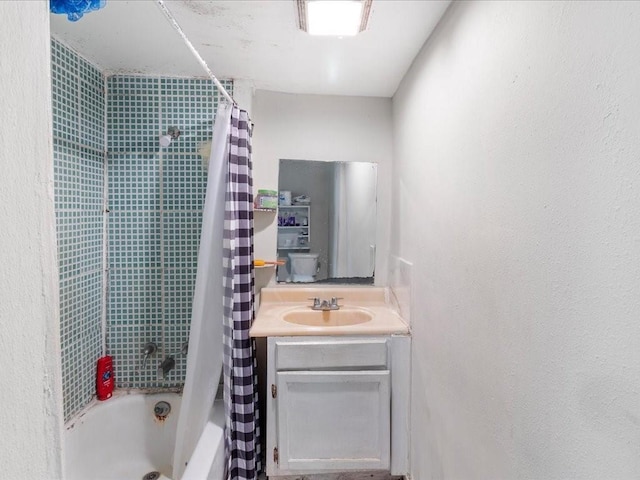 bathroom featuring shower / bath combination with curtain, a textured wall, and vanity