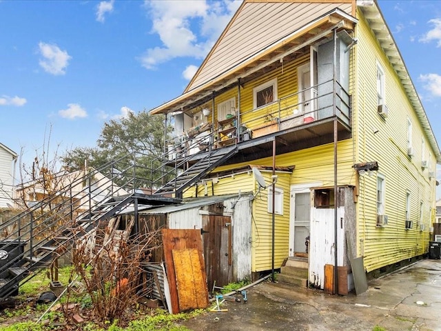 rear view of property with entry steps and a balcony