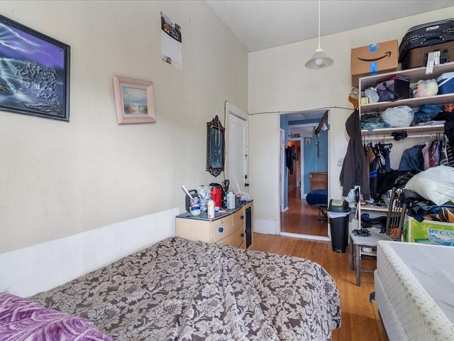 bedroom with a towering ceiling, a closet, and wood finished floors