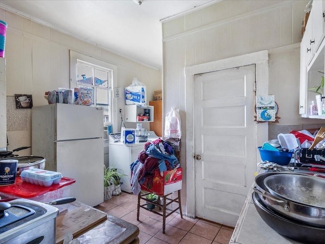 kitchen featuring white cabinets, washer / clothes dryer, tile patterned floors, freestanding refrigerator, and a sink