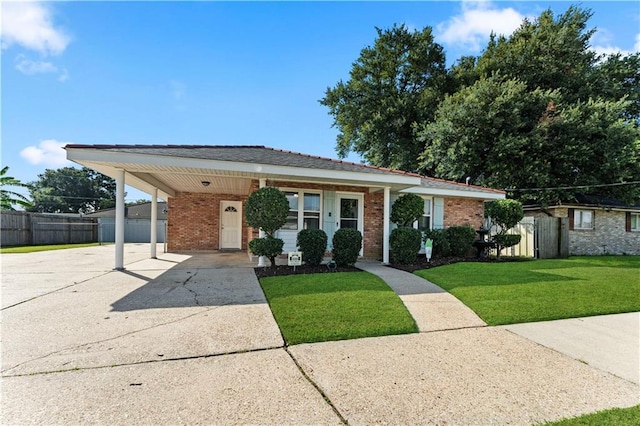 view of front of home featuring brick siding, fence, driveway, a carport, and a front yard