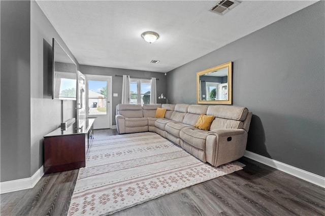 living room featuring dark wood-type flooring, visible vents, and baseboards