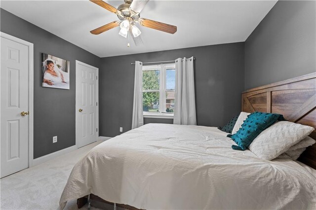 bedroom featuring a ceiling fan, light colored carpet, and baseboards