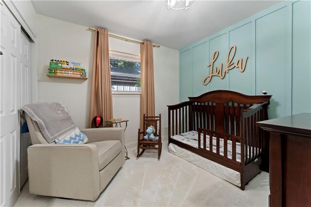 carpeted bedroom featuring a crib, a decorative wall, and a closet