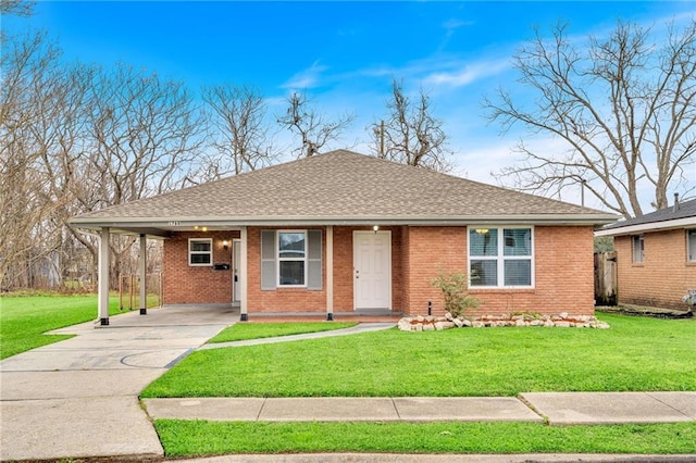 view of front of property with a front yard, concrete driveway, brick siding, and an attached carport