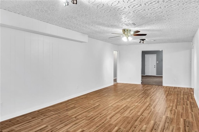 unfurnished room featuring a ceiling fan, a textured ceiling, baseboards, and wood finished floors