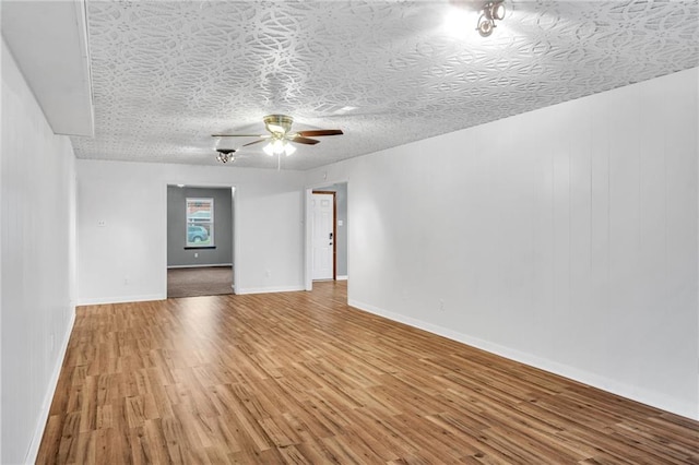 spare room featuring ceiling fan, a textured ceiling, wood finished floors, and baseboards