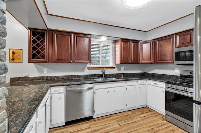 kitchen with light wood finished floors, appliances with stainless steel finishes, a sink, and crown molding