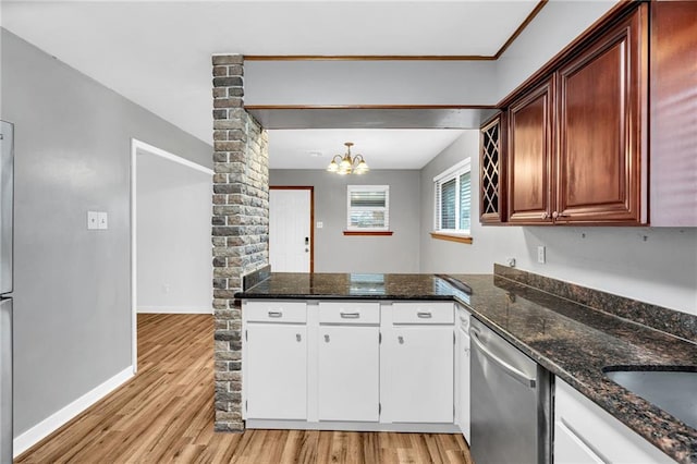 kitchen with baseboards, light wood-style flooring, dark stone countertops, ornate columns, and stainless steel dishwasher