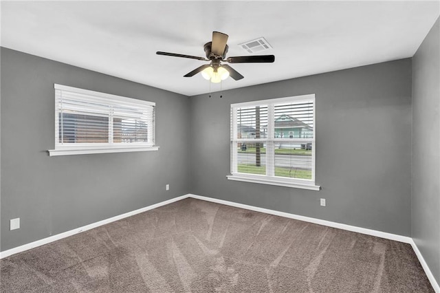 carpeted spare room with visible vents, baseboards, and a ceiling fan