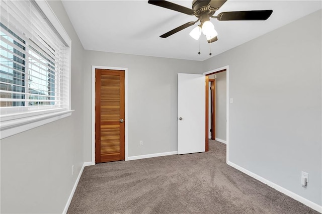 unfurnished bedroom with ceiling fan, a closet, baseboards, and carpet flooring