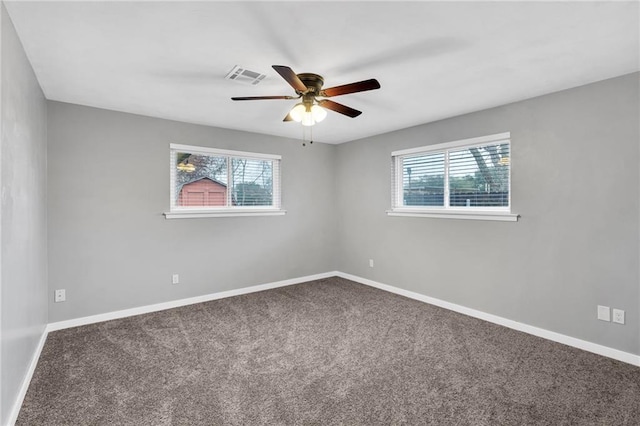 carpeted empty room featuring plenty of natural light, visible vents, and baseboards