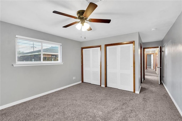 unfurnished bedroom with a ceiling fan, baseboards, multiple closets, and carpet flooring