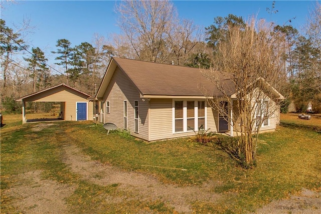 view of side of home featuring dirt driveway and a yard